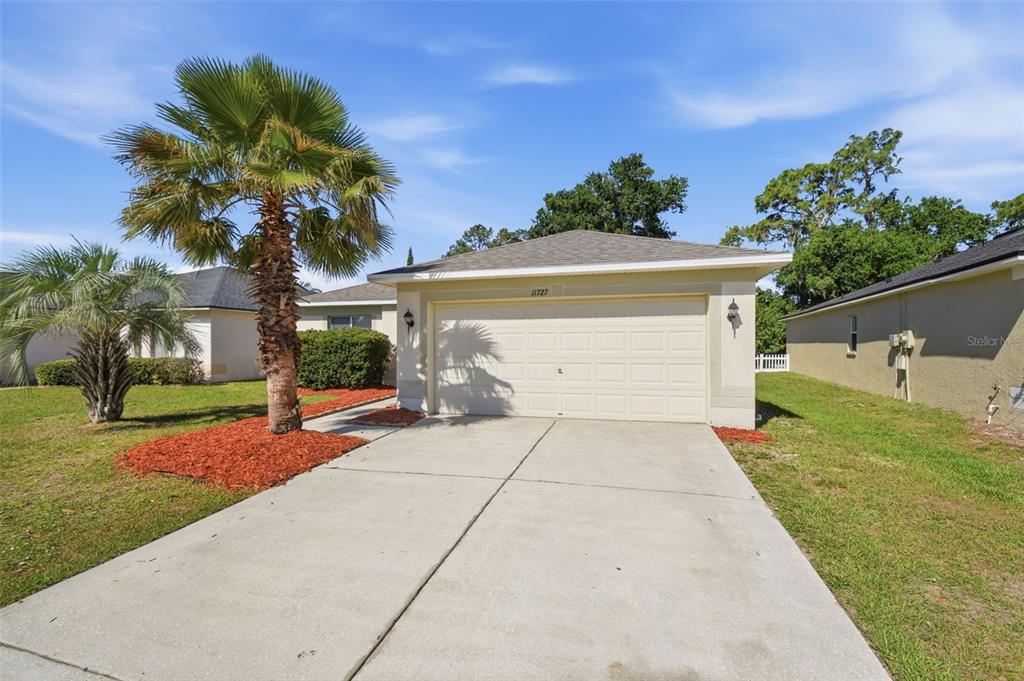 A beige house with a two-car garage and a palm tree in the front yard — 11727 BRENFORD CREST DRIVE, RIVERVIEW, FL