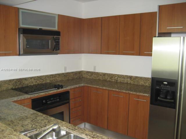 A kitchen features wood cabinets, granite countertops, and stainless steel appliances — 9066 SW 73 CT # 1702, Miami FL 33156, MIAMI, FL
