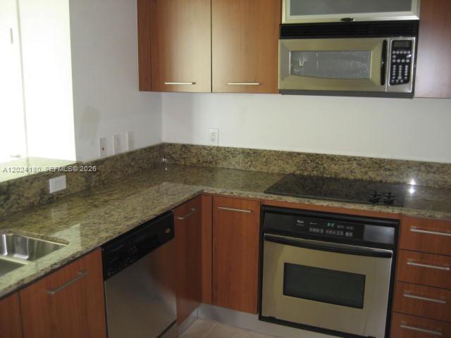 A kitchen features wood cabinets, granite countertops, a stainless steel oven, and a microwave — 9066 SW 73 CT # 1702, Miami FL 33156, MIAMI, FL
