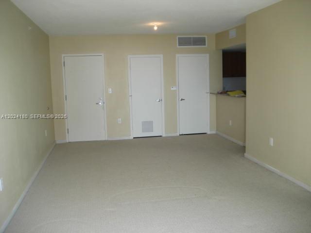 An interior view of a room with beige walls, carpeted flooring, and three white doors — 9066 SW 73 CT # 1702, Miami FL 33156, MIAMI, FL
