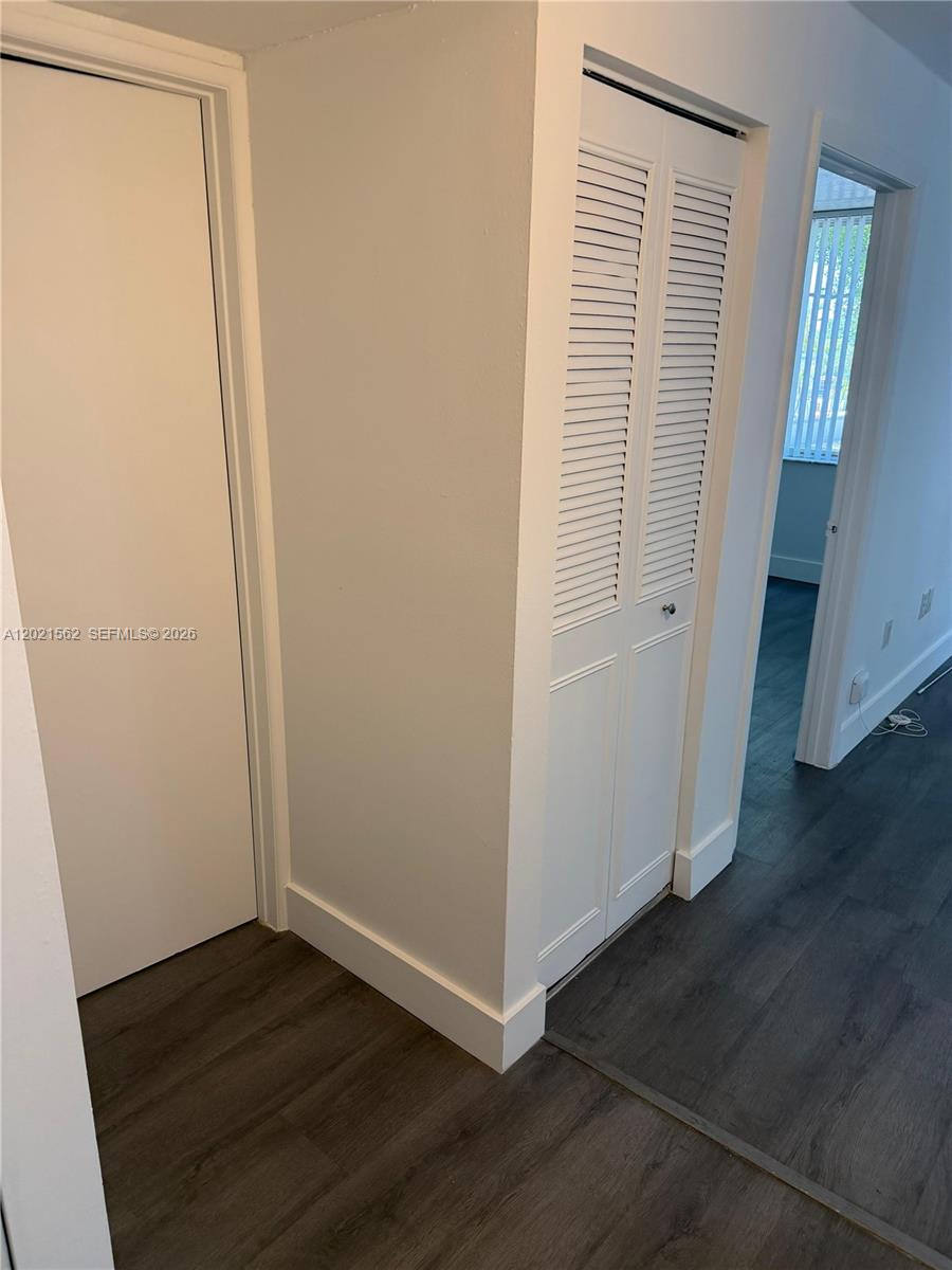 A hallway features a solid white door, a louvered closet door, and dark wood flooring — 1740 NW N River Dr # 325, Miami FL 33125, MIAMI, FL