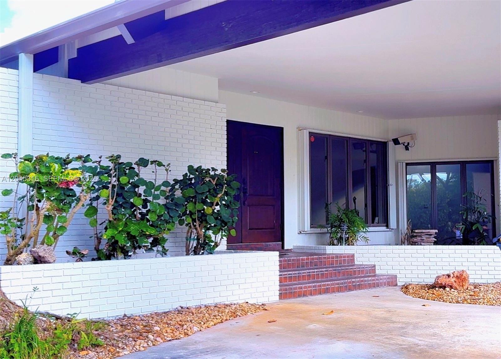 A white brick planter and steps lead to the dark wood front door of a house — 8925 SW 102nd Ter # 0, Miami FL 33176, MIAMI, FL