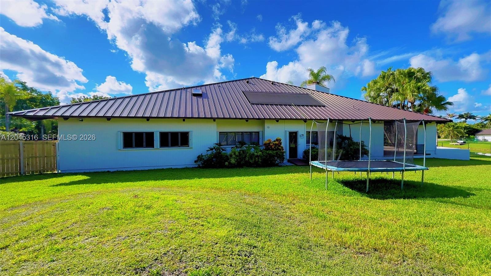 The exterior of a single-story house features a metal roof and a backyard trampoline — 8925 SW 102nd Ter # 0, Miami FL 33176, MIAMI, FL
