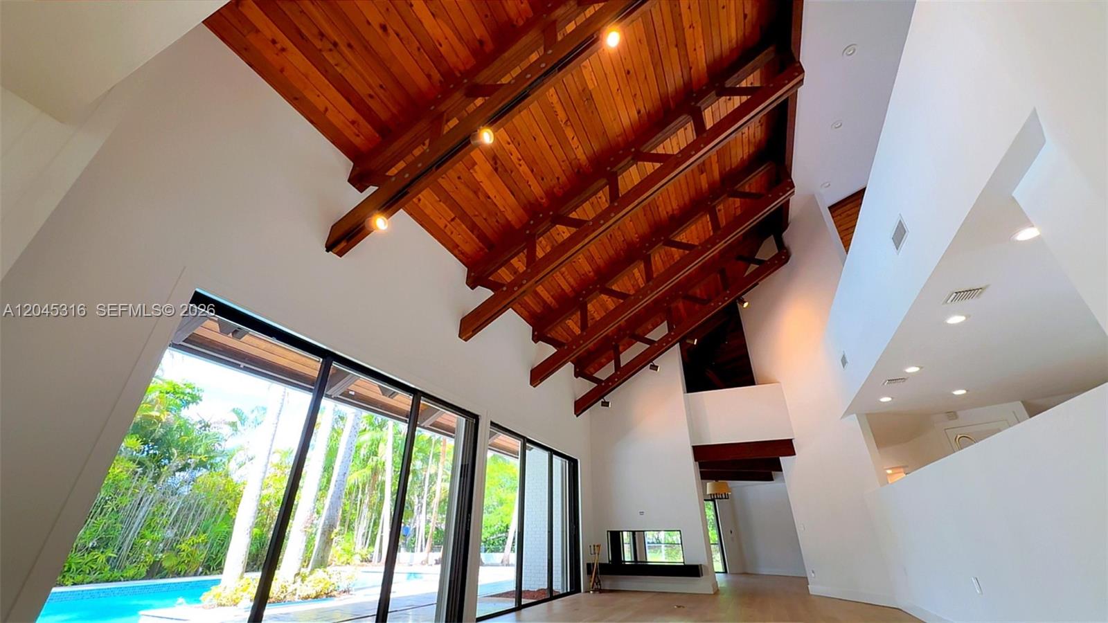 A spacious living area features a vaulted wood-beamed ceiling, white walls, and large glass doors — 8925 SW 102nd Ter # 0, Miami FL 33176, MIAMI, FL