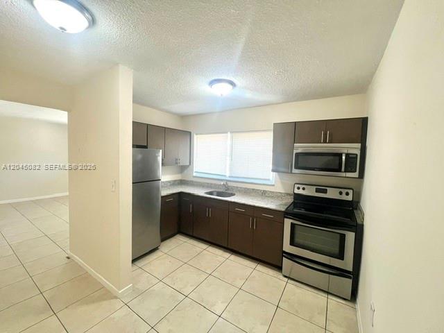 This kitchen features dark wood cabinets, stainless steel appliances, and light-colored tile flooring — 7626 NE 6th Ct # 5, Miami FL 33138, MIAMI, FL