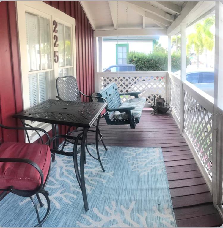 A covered porch features a small table, chairs, a hanging bench, and a blue area rug — 225 SULLIVAN STREET, PUNTA GORDA, FL
