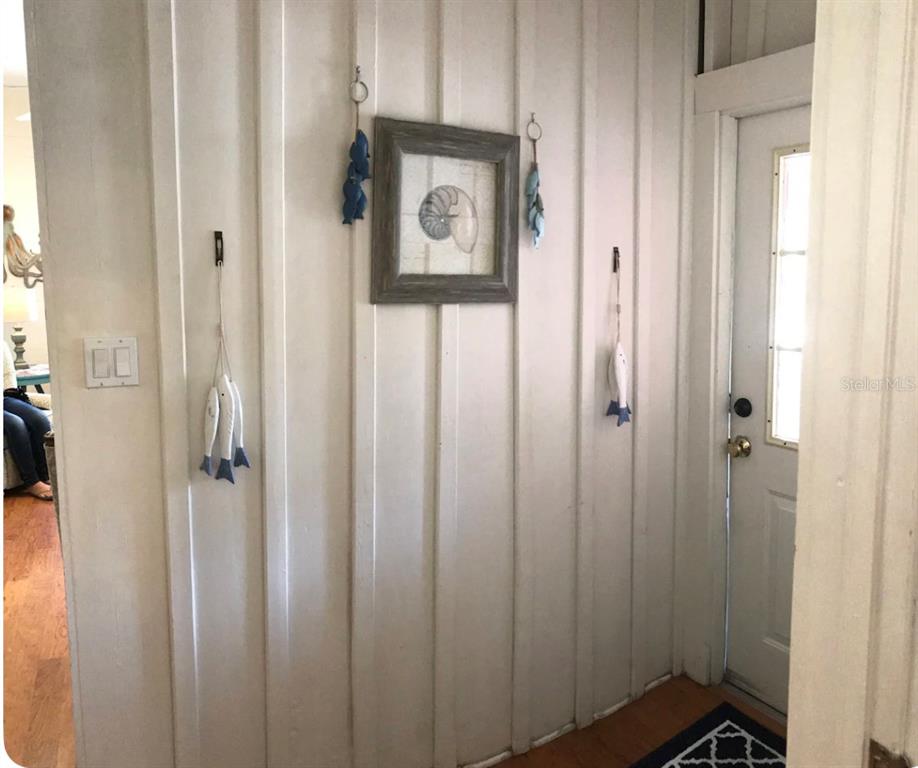 A white paneled entryway features a framed seashell print and hanging coastal-themed wall decorations — 225 SULLIVAN STREET, PUNTA GORDA, FL