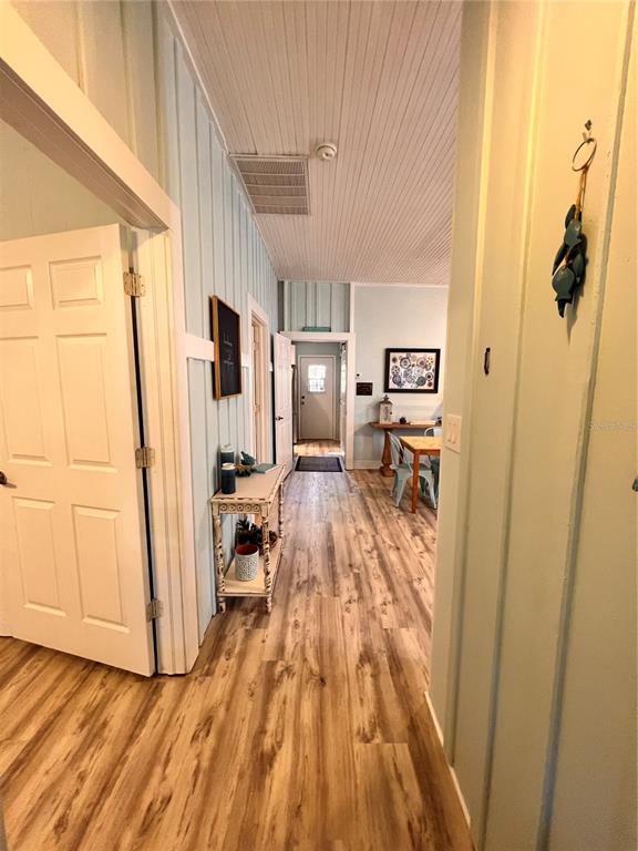 A hallway with light blue vertical paneling, wood-look flooring, and a small wooden console table — 225 SULLIVAN STREET, PUNTA GORDA, FL