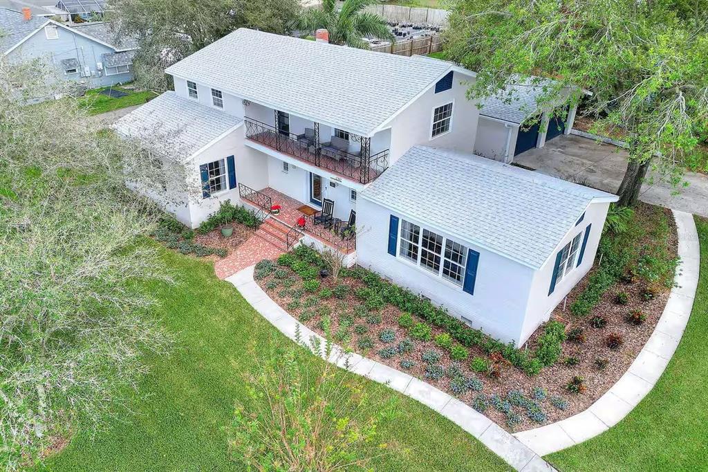 An aerial view of a two-story white house with a brick walkway and metal balcony — 1302 LAKE ELBERT DR SE, WINTER HAVEN, FL