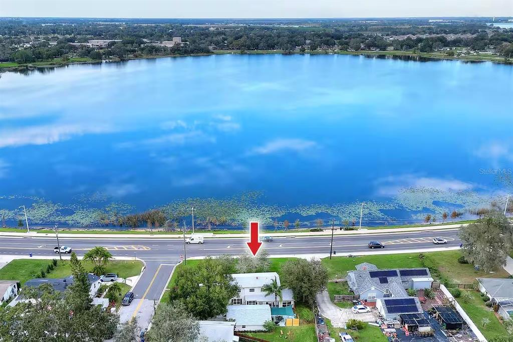 An aerial view shows a house situated next to a road and a large lake — 1302 LAKE ELBERT DR SE, WINTER HAVEN, FL