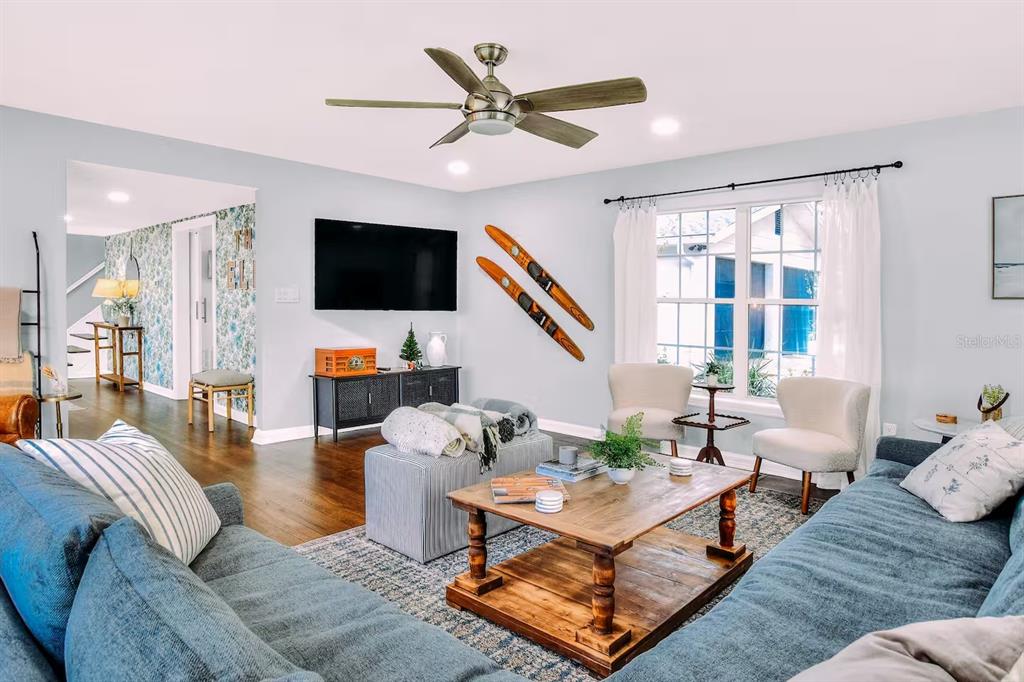 A living room features a blue sectional sofa, a wooden coffee table, and vintage wall skis — 1302 LAKE ELBERT DR SE, WINTER HAVEN, FL