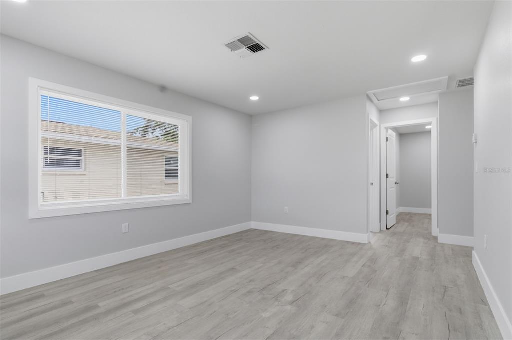 An empty bedroom features light gray walls, wood-look flooring, recessed lighting, and a large window — 3042 BAHIA AVENUE, HOLIDAY, FL