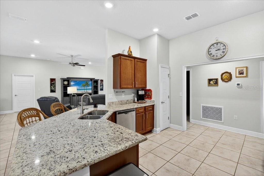 A kitchen with granite countertops and wood cabinets overlooks an adjacent living room area — 118 RYBERRY DRIVE, PALM COAST, FL