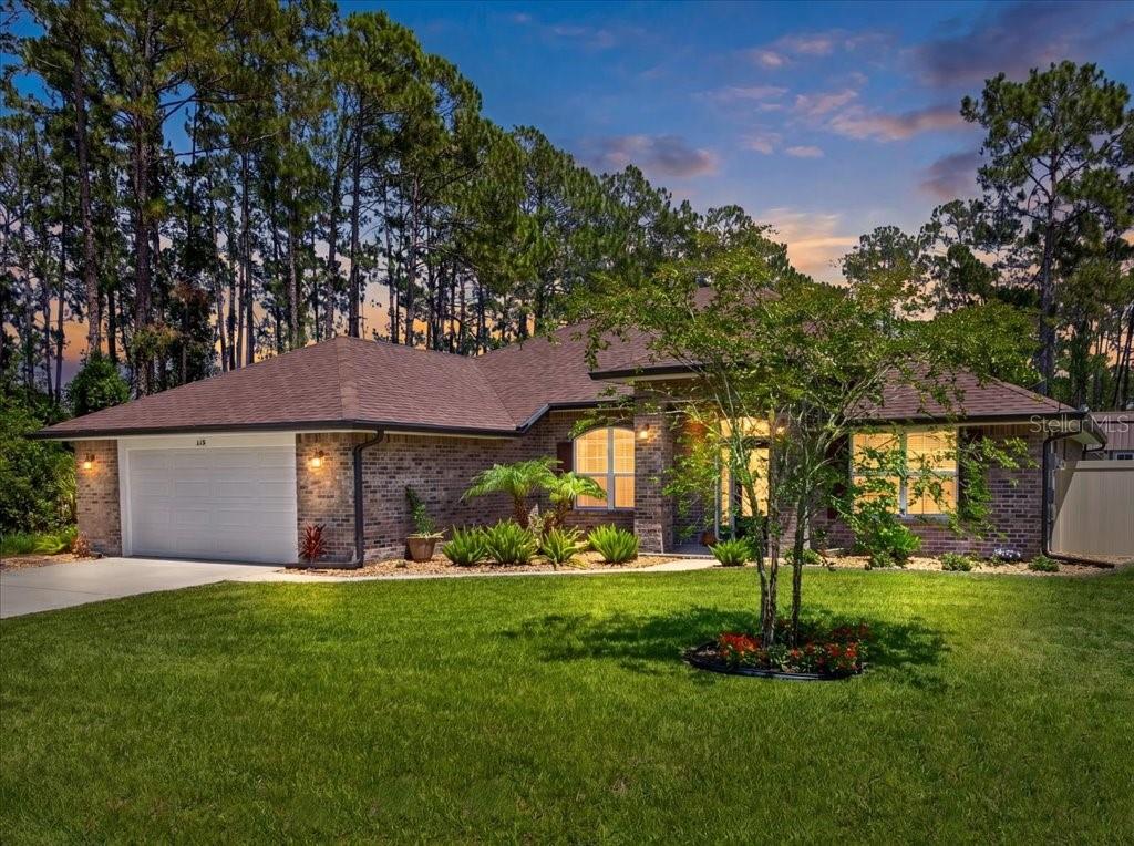 A single-story brick house with a two-car garage sits behind a green lawn — 118 RYBERRY DRIVE, PALM COAST, FL
