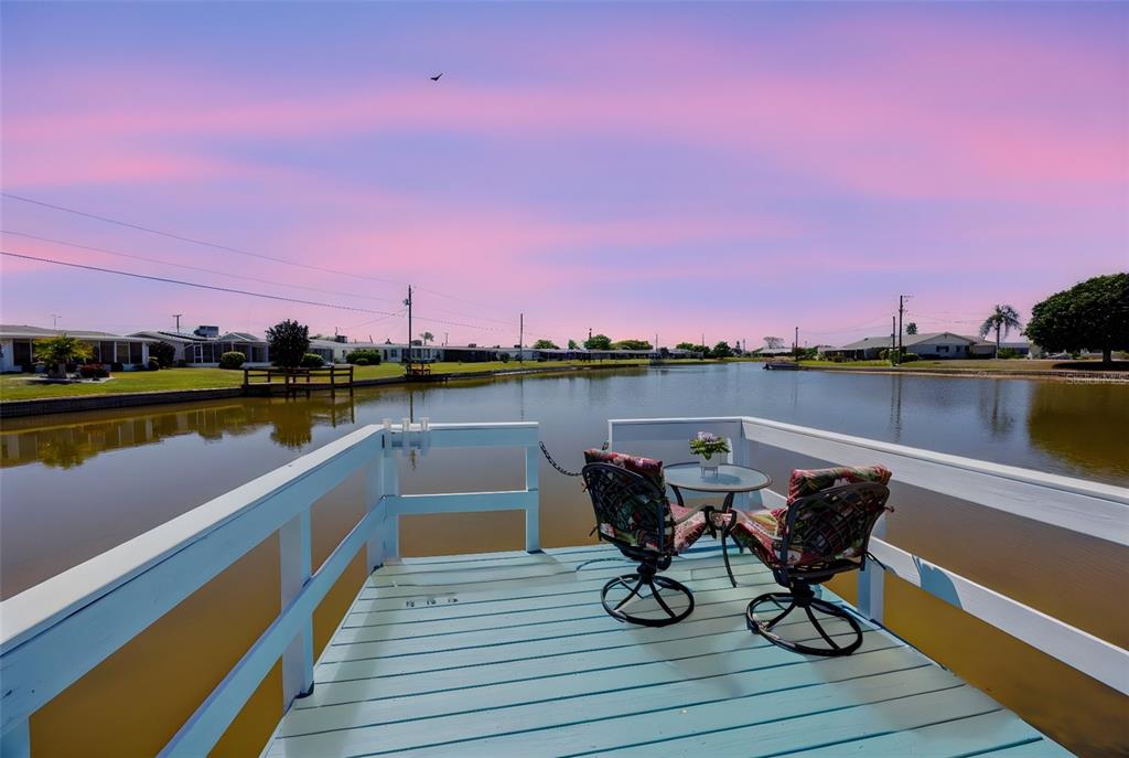 An aerial view of a single-story house with a white exterior, garage, and waterfront backyard — 1704 DANBURY DRIVE, SUN CITY CENTER, FL