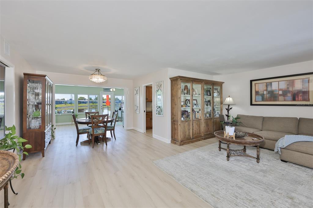 A living room and dining area with light wood floors, a sectional, and display cabinets — 1704 DANBURY DRIVE, SUN CITY CENTER, FL