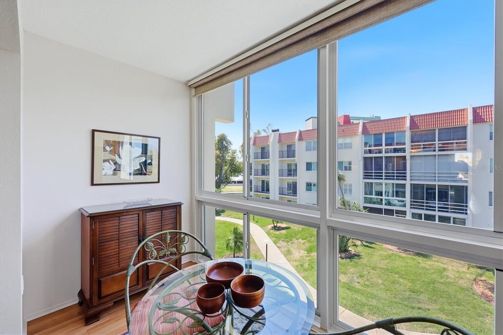 A dining area features a glass table, wooden cabinet, and large windows overlooking a courtyard — 220 SANTA MARIA STREET UNIT 342, VENICE, FL