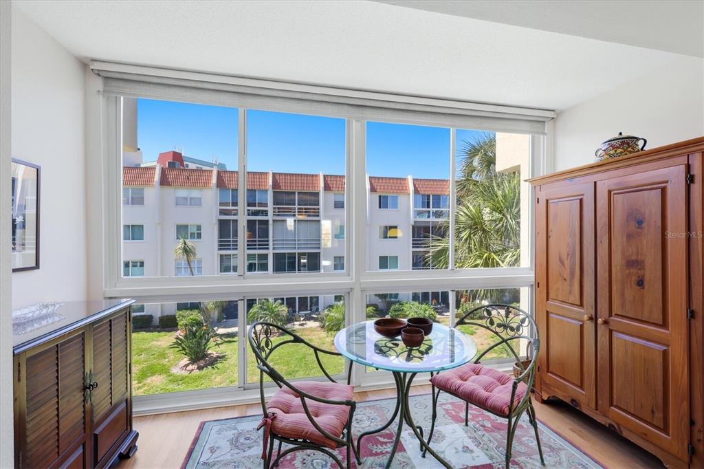 A sunroom features a glass-topped table, two chairs, and a large window overlooking an apartment complex — 220 SANTA MARIA STREET UNIT 342, VENICE, FL