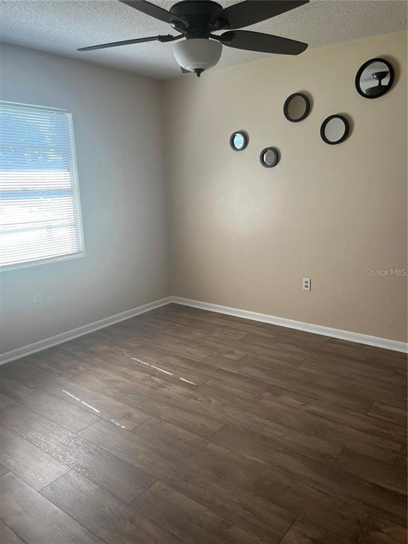 An empty bedroom features wood-look flooring, a ceiling fan, and circular wall mirrors — 2112 W MARTIN STREET, KISSIMMEE, FL