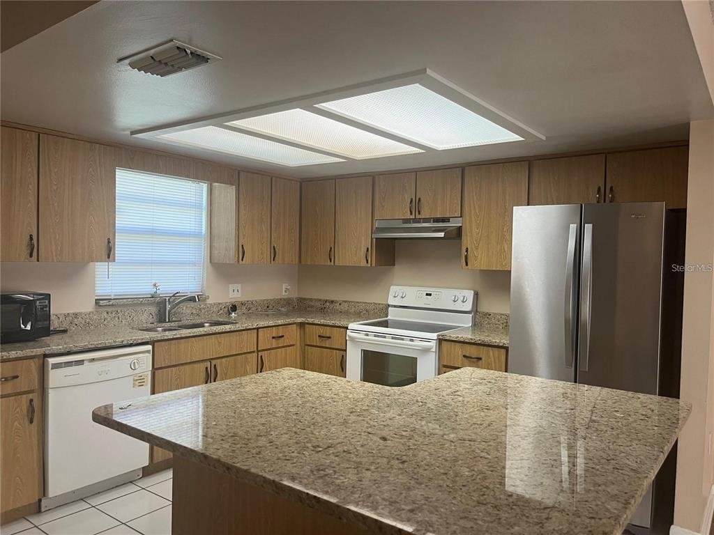 A kitchen features light wood cabinets, granite countertops, stainless steel appliances, and a central island — 2112 W MARTIN STREET, KISSIMMEE, FL