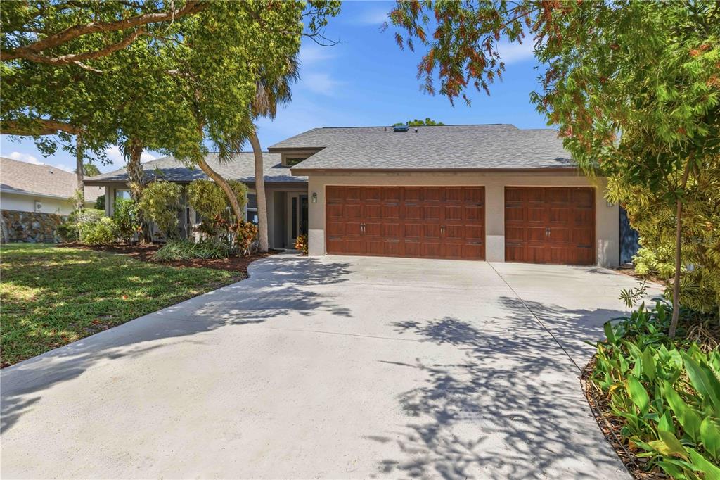 A single-story house with a three-car garage and a concrete driveway under large trees — 3953 PRAIRIE DUNES DRIVE, SARASOTA, FL