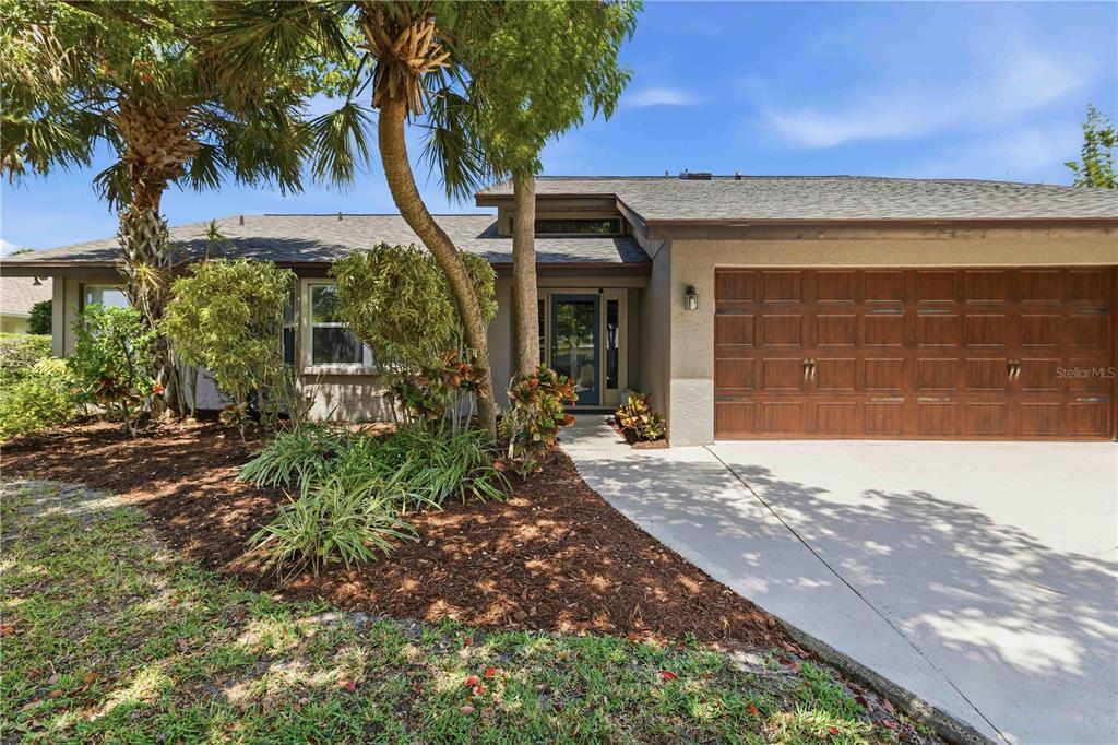 A single-story house with a brown garage door, a blue front door, and palm trees — 3953 PRAIRIE DUNES DRIVE, SARASOTA, FL