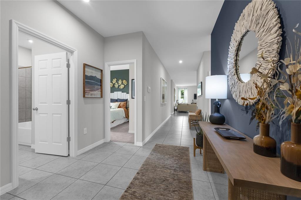 A hallway with gray tile flooring leads past a bathroom and bedroom to a living area — 6767 WINTERBERRY DRIVE, LAKE HAMILTON, FL