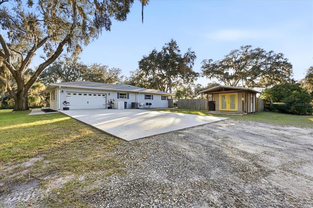 A single-story house with a white garage and a detached shed on a gravel lot — 30424 HILLSIDE LANE, WESLEY CHAPEL, FL