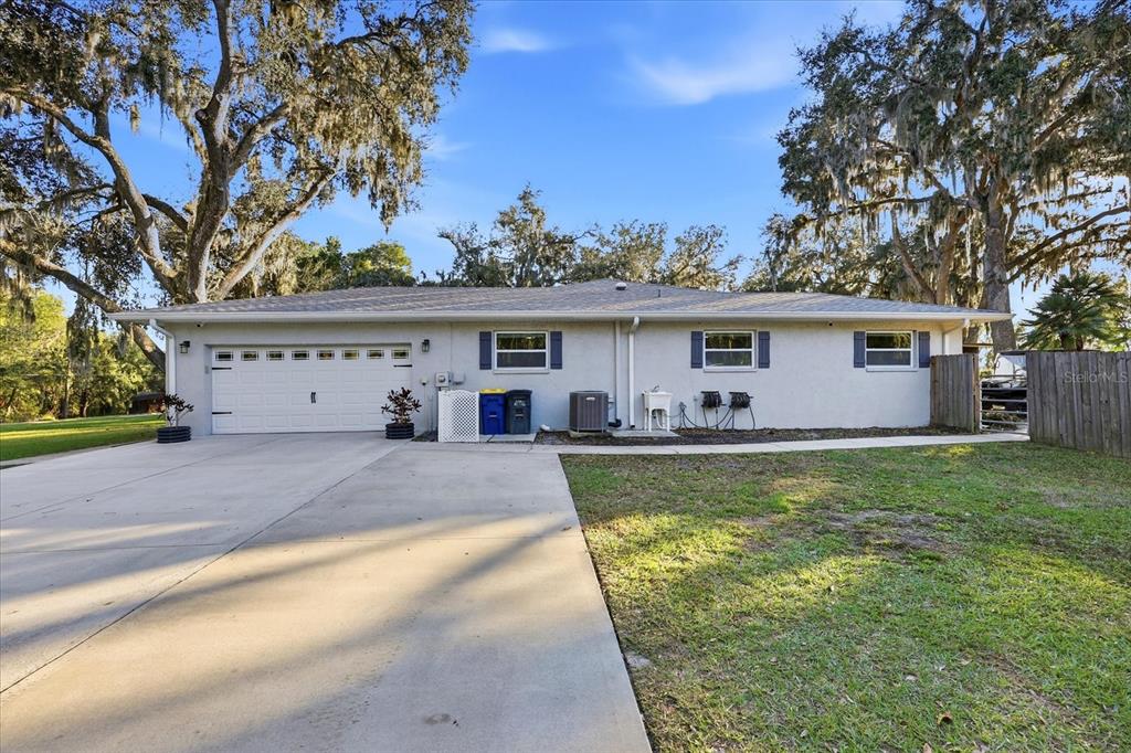 A single-story house with a white exterior, a two-car garage, and large oak trees — 30424 HILLSIDE LANE, WESLEY CHAPEL, FL