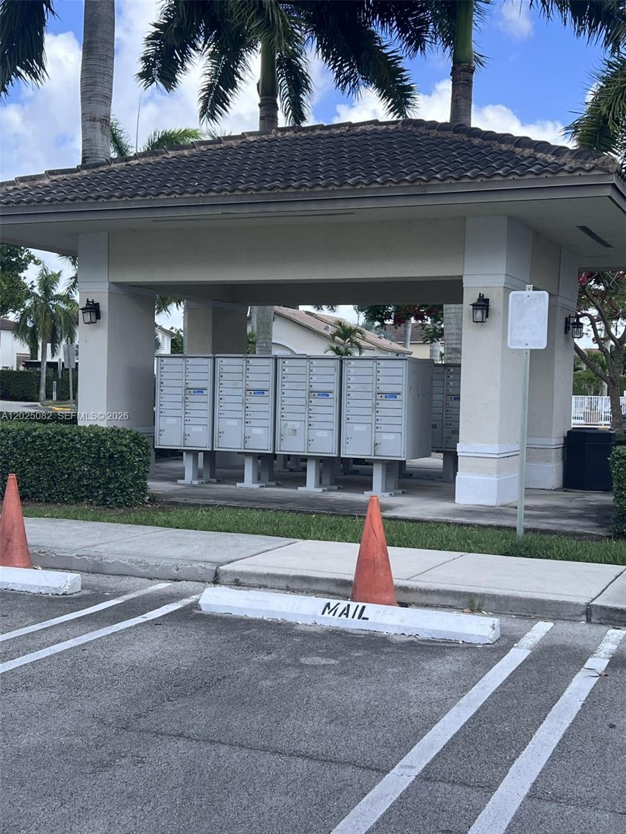 An outdoor covered mail kiosk with multiple metal mailboxes stands in a parking lot — 11601 NW 89th St # 222, Doral FL 33178, DORAL, FL