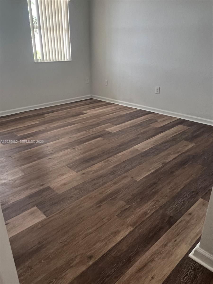 An empty room features light gray walls, white baseboards, and wood-look plank flooring — 11601 NW 89th St # 222, Doral FL 33178, DORAL, FL