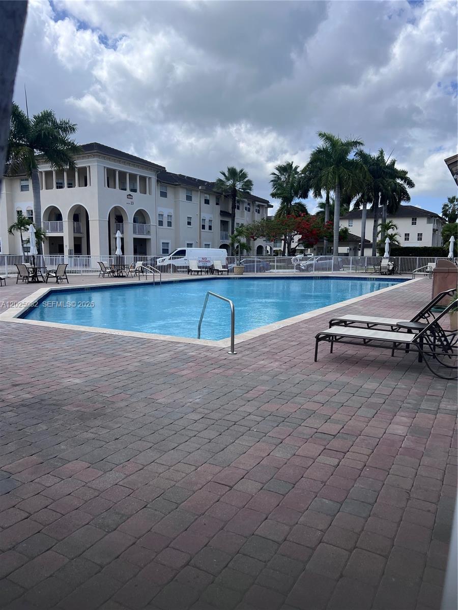 A swimming pool sits in front of a multi-story apartment building with palm trees — 11601 NW 89th St # 222, Doral FL 33178, DORAL, FL