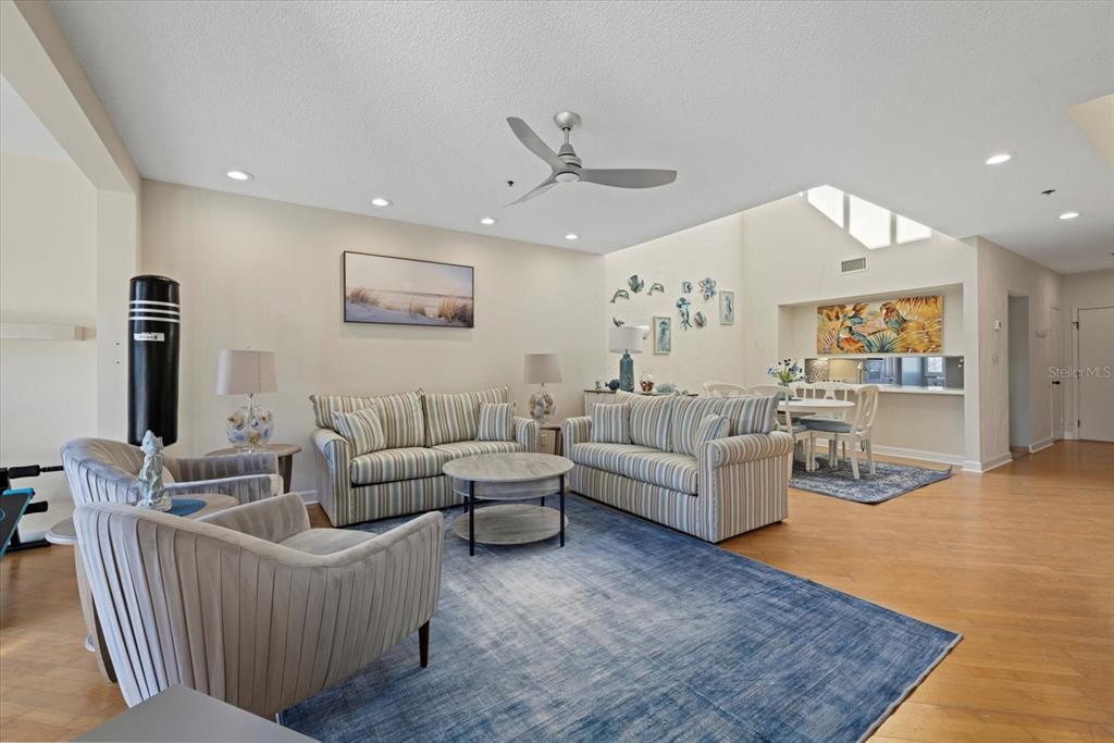 A living room with striped sofas, a blue area rug, and an adjacent dining area — 1928 HARBOURSIDE DRIVE UNIT 1402, LONGBOAT KEY, FL