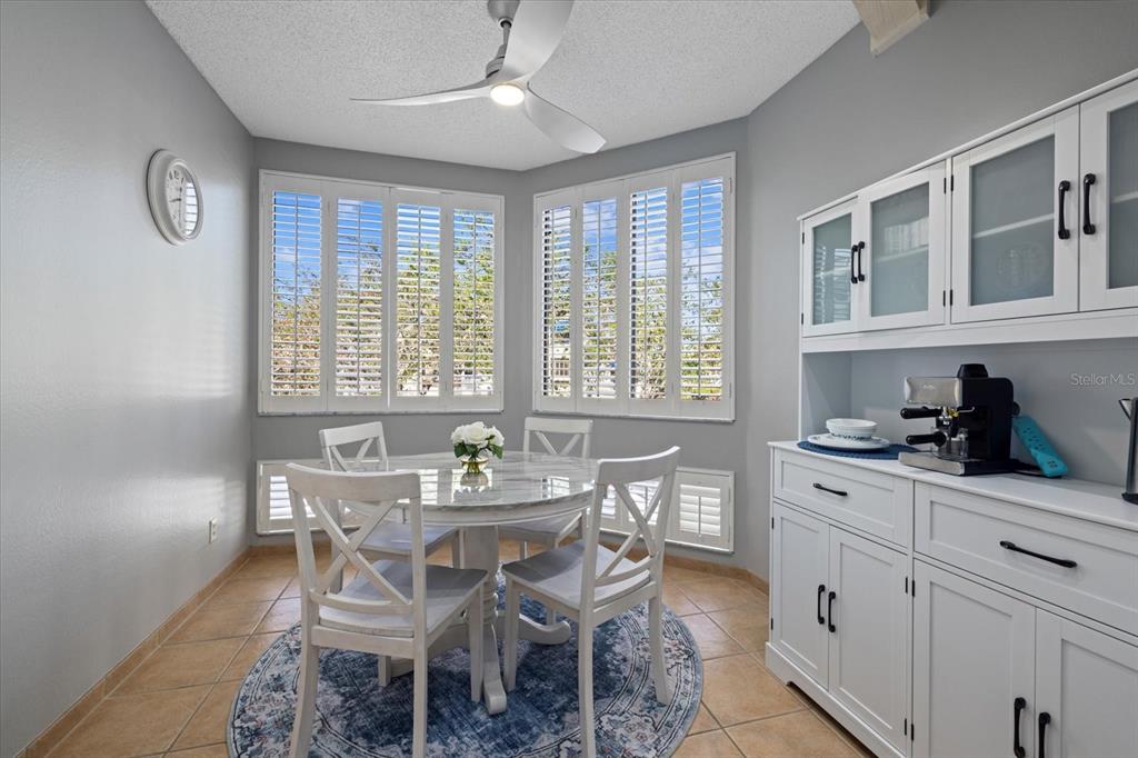 A dining area features a round table, four white chairs, and a white hutch cabinet — 1928 HARBOURSIDE DRIVE UNIT 1402, LONGBOAT KEY, FL