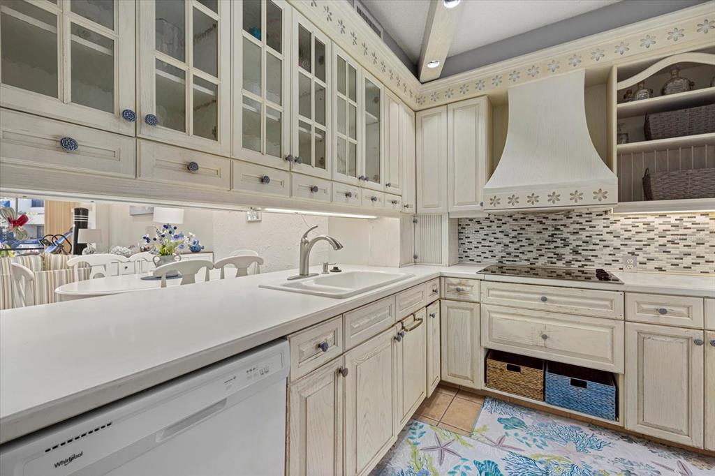 A kitchen features white cabinets, a white farmhouse sink, and a tiled backsplash — 1928 HARBOURSIDE DRIVE UNIT 1402, LONGBOAT KEY, FL