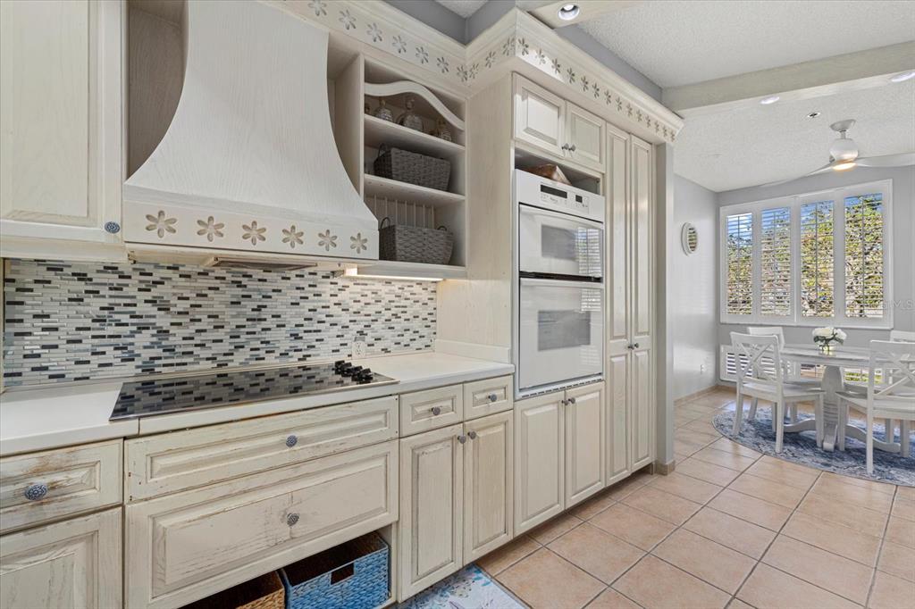 A kitchen features cream-colored cabinetry, a mosaic tile backsplash, a double oven, and tile flooring — 1928 HARBOURSIDE DRIVE UNIT 1402, LONGBOAT KEY, FL