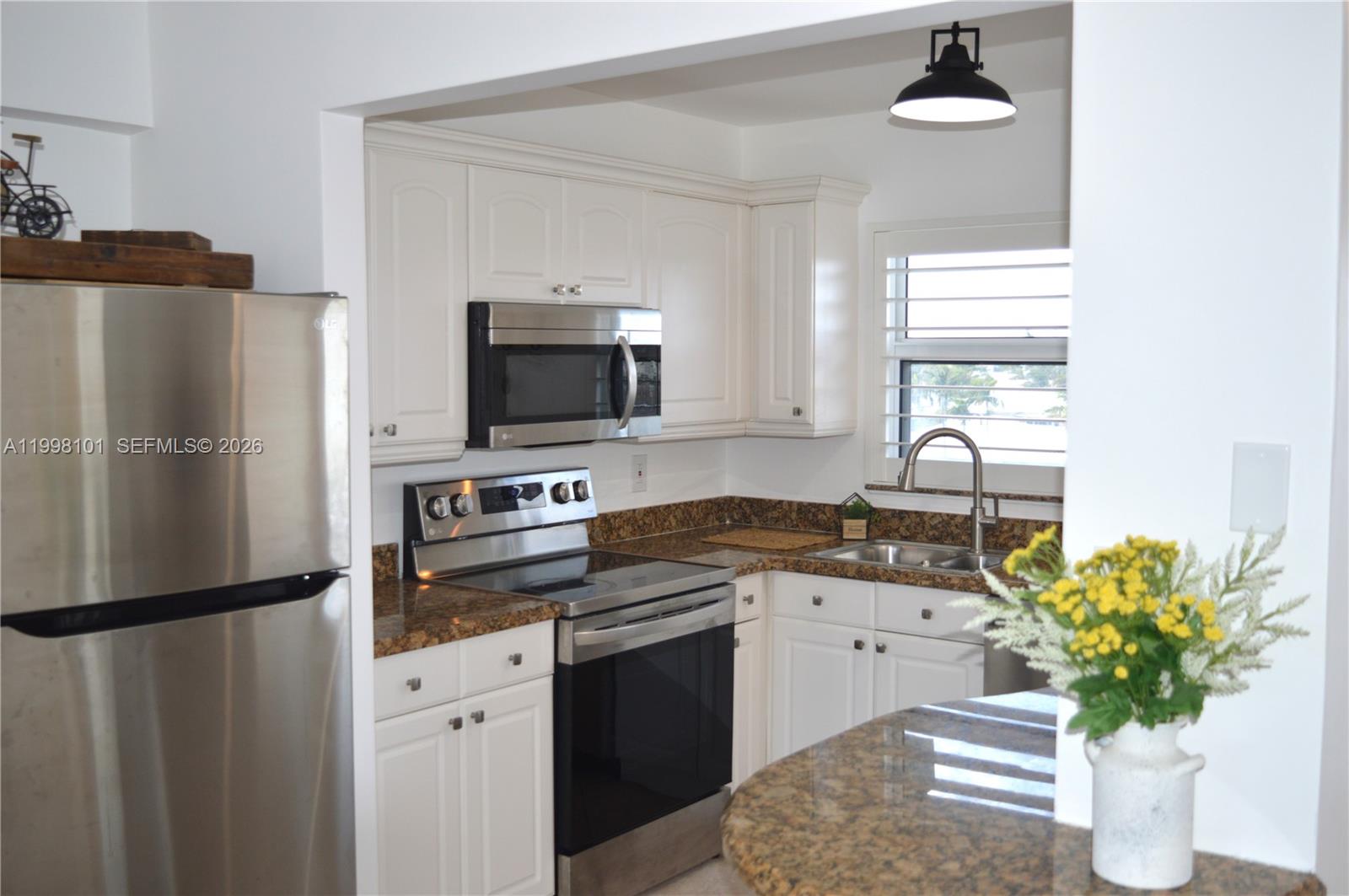 A kitchen features white cabinets, stainless steel appliances, and brown granite countertops — 1511 SE 15th Ct # 403, Deerfield Beach FL 33441, DEERFIELD BEACH, FL