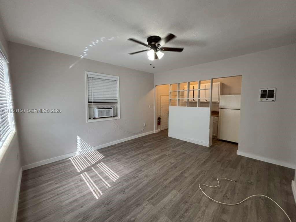 A living room with gray wood-look flooring, a ceiling fan, and an open kitchen partition — 301 Sharar Ave # 4, Opa-Locka FL 33054, OPA-LOCKA, FL
