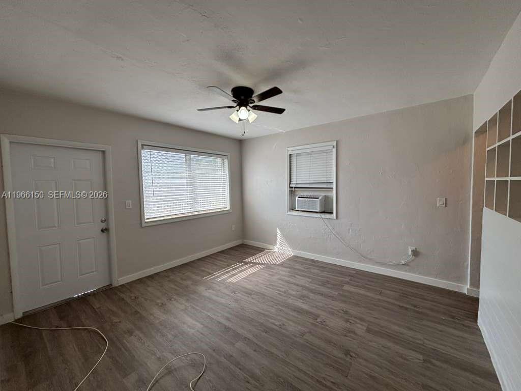 An empty room features light gray walls, wood-look flooring, a ceiling fan, and two windows — 301 Sharar Ave # 4, Opa-Locka FL 33054, OPA-LOCKA, FL