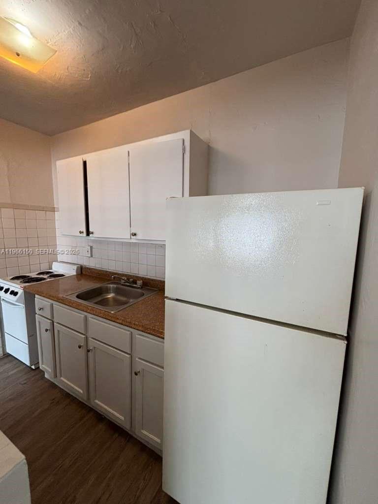 A small kitchen features white cabinets, a white refrigerator, and a brown countertop — 301 Sharar Ave # 4, Opa-Locka FL 33054, OPA-LOCKA, FL