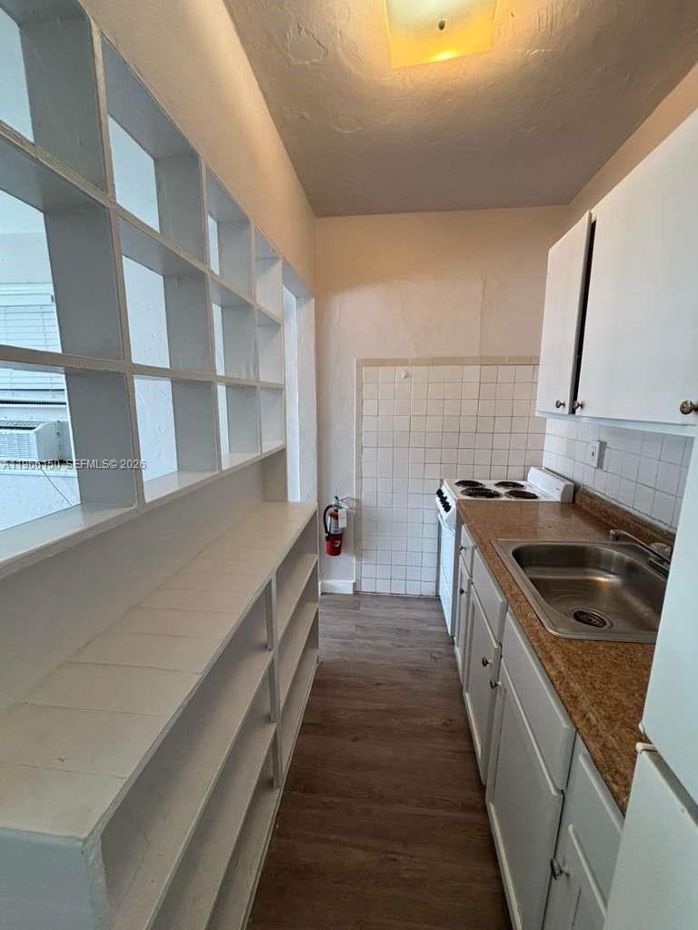 A narrow kitchen features white open shelving, a small electric stove, and a stainless sink — 301 Sharar Ave # 4, Opa-Locka FL 33054, OPA-LOCKA, FL