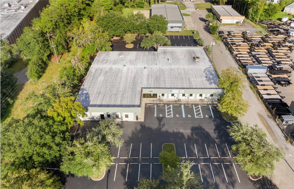 An aerial view shows a commercial building with a large parking lot and adjacent trailers — 5719 NW 13TH STREET, GAINESVILLE, FL