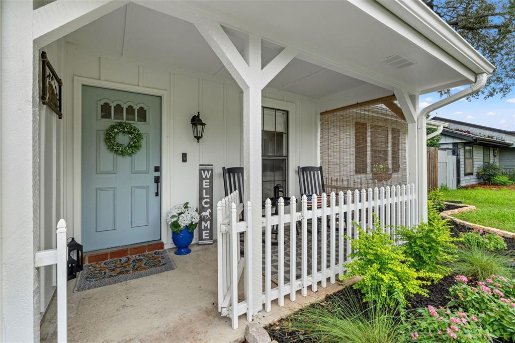 A light blue front door with a wreath opens onto a covered porch with white fencing — 8449 VALMORA STREET, SPRING HILL, FL