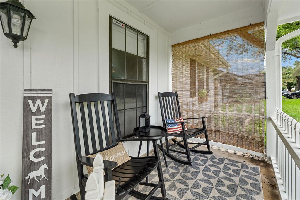 A covered front porch features two black rocking chairs, a small table, and a welcome sign — 8449 VALMORA STREET, SPRING HILL, FL