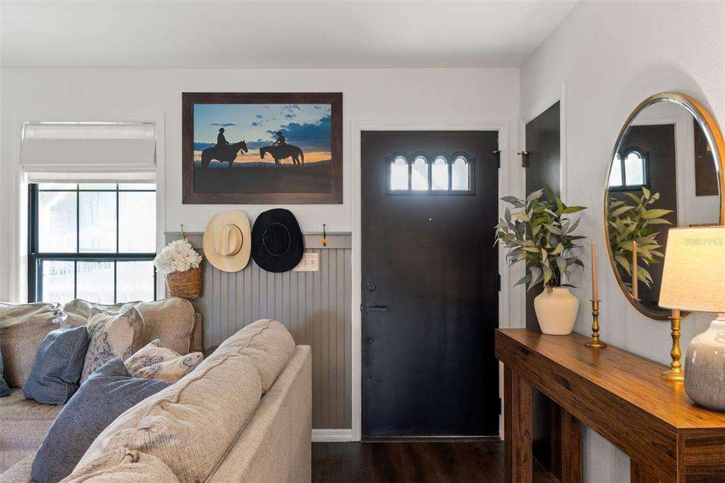 A living room entryway features a black door, a console table, and western-themed wall decor — 8449 VALMORA STREET, SPRING HILL, FL