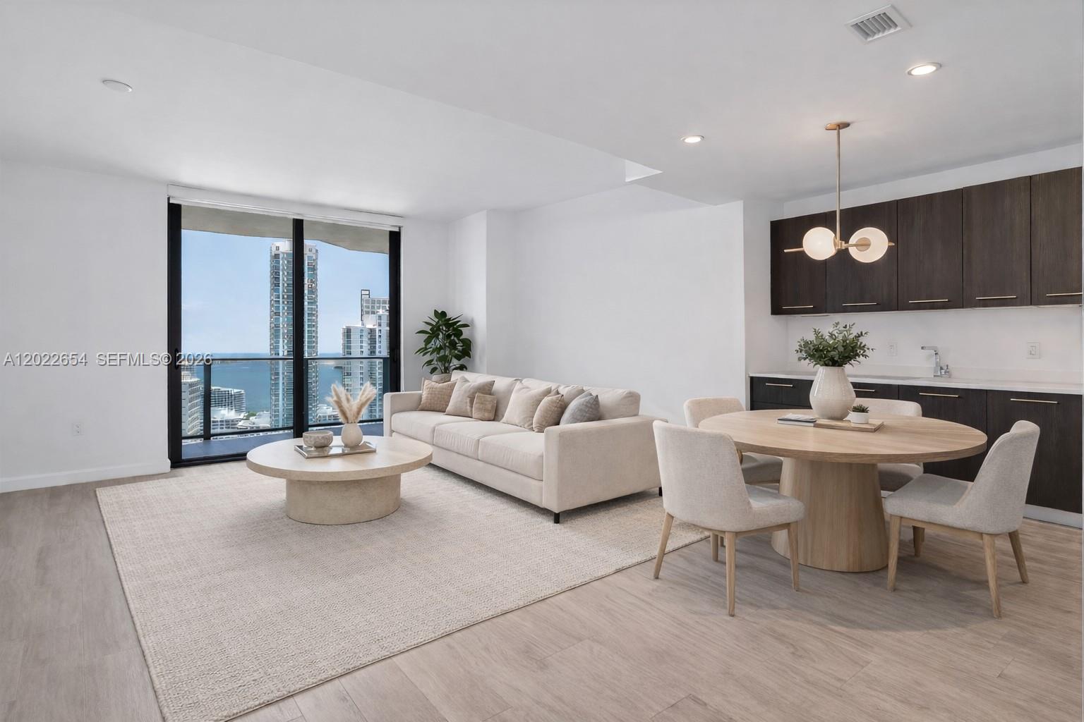 A modern living and dining area features a neutral sofa, round table, and floor-to-ceiling windows — 45 SW 9th St # 3502, Miami FL 33130, MIAMI, FL