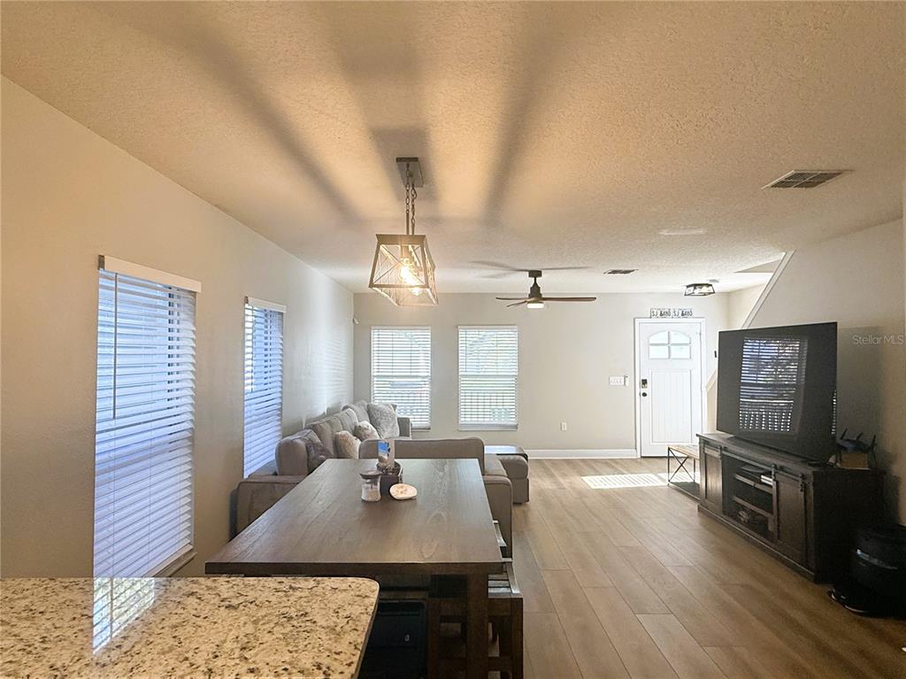 An open-concept living and dining area features wood-look flooring, a dining table, and a sofa — 1934 W SPRUCE STREET, TAMPA, FL