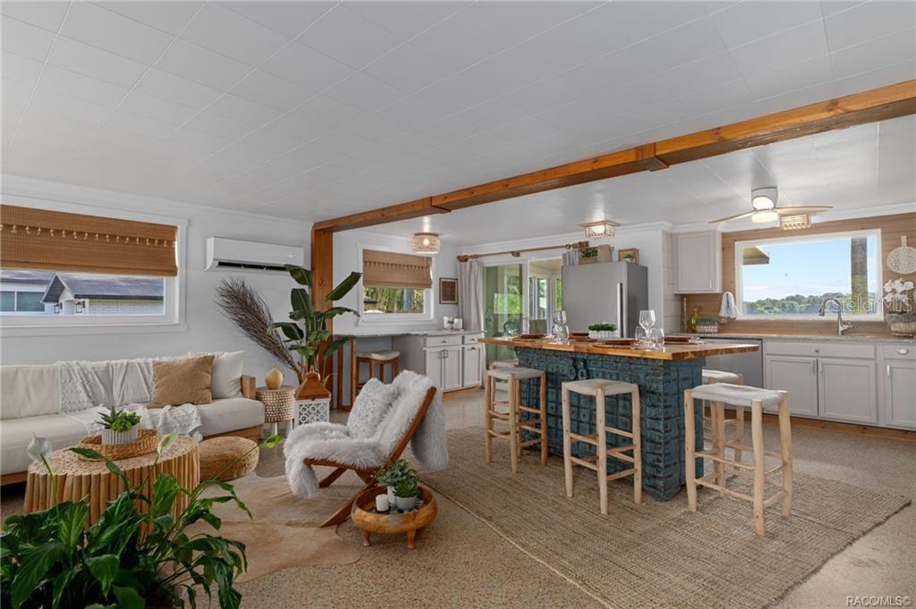 An open-concept living room and kitchen featuring a blue carved wood island and wood beams — 412 ELLA AVENUE, INVERNESS, FL