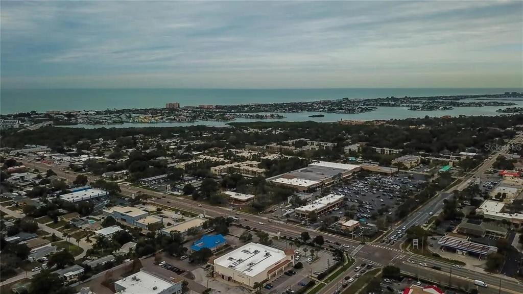 An aerial view shows a commercial shopping center and surrounding residential area near the coast — 11485 OAKHURST ROAD UNIT -211, LARGO, FL