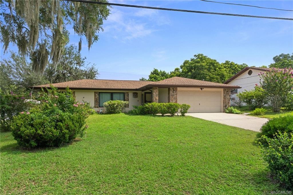 A single-story house with a tan exterior, a two-car garage, and a large front lawn — 206 HEMLOCK STREET, INVERNESS, FL